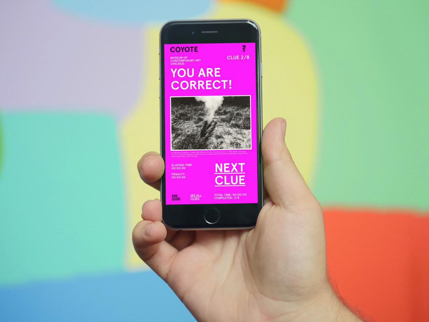 A light-skinned hand holds up a smartphone with the screen facing you. The screen reads, "YOU ARE CORRECT!" at the top and "NEXT CLUE" in the bottom right-hand corner.